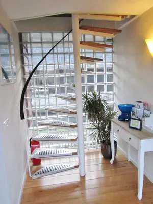 a spiral staircase in a room with a desk at Bed & Breakfast Kortenhoefsedijk in Kortenhoef