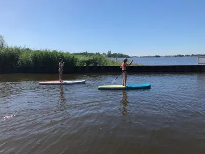 two people are standing on paddle boards in the water at Bed & Breakfast Kortenhoefsedijk in Kortenhoef