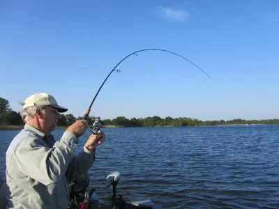 a man holding a fishing rod on a lake at Bed & Breakfast Kortenhoefsedijk in Kortenhoef