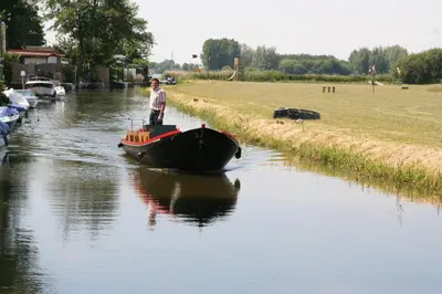 a man standing on a boat in a canal at De Vooroever in Wervershoof