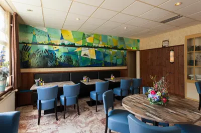a restaurant with two tables and chairs and a painting at De Vooroever in Wervershoof