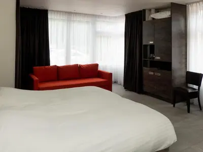 a hotel room with a bed and a red couch at Hotel-Restaurant Het Rechthuis in Muiderberg