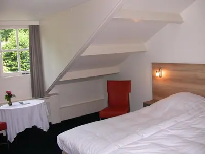 a hotel room with a bed and a red chair at Hotel-Restaurant Het Rechthuis in Muiderberg
