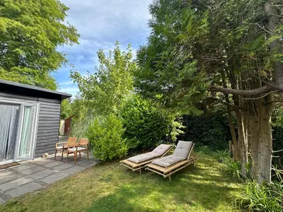 a garden with two lounge chairs under a tree at Zen in Schoorl in Schoorl