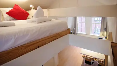 a bedroom with a large white bed with red pillows at Loft Leidsegracht in Amsterdam