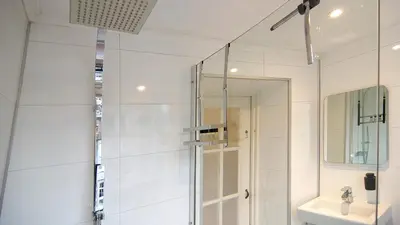 a white bathroom with a shower and a sink at Loft Leidsegracht in Amsterdam