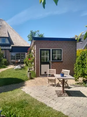 a patio with two chairs and a table in front of a house at de Vrijheid in Groet