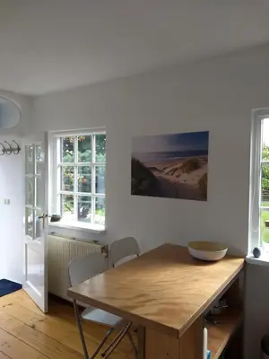 a dining room with a wooden table and two windows at de Vrijheid in Groet