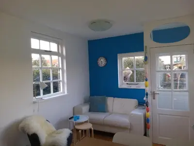 a living room with a white couch and blue walls at de Vrijheid in Groet
