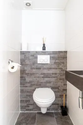 a bathroom with a white toilet and a brick wall at Yess in Vinkeveen