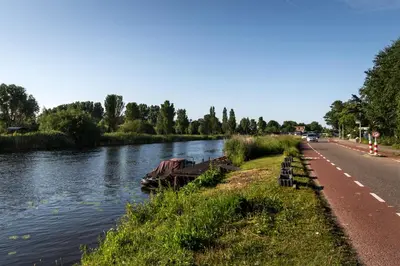a river with a boat on the side of a road at B&B Nieuwe Brug in Vijfhuizen