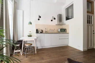 a kitchen with white cabinets and a small table at Studio Jan Steen in Amsterdam