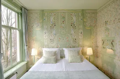 a bedroom with a white bed with floral wallpaper at 't Hotel in Amsterdam