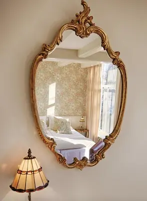 a mirror on a wall with a bed and a lamp at 't Hotel in Amsterdam