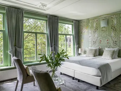 a bedroom with a large bed and windows at 't Hotel in Amsterdam