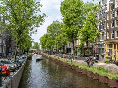 a canal in a city with cars and buildings at 't Hotel in Amsterdam