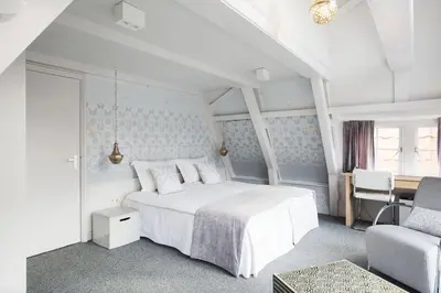 a white bedroom with a bed and a chair at 't Hotel in Amsterdam