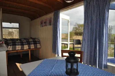 a room with a bed and a table and a window at Sitting at the Bay in Zuiderwoude