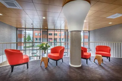 a waiting room with red chairs and a column at Joy Hotel in Amsterdam
