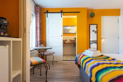 a bedroom with yellow walls and a table and a bed at B&B Little Miss Sunshine in Zandvoort