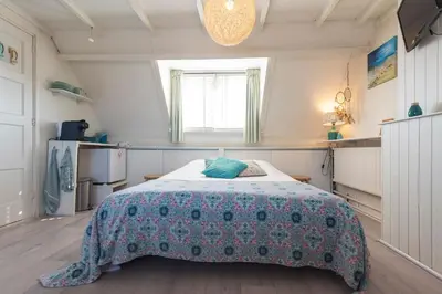 a bedroom with a bed with a floral bedspread at B&B Little Miss Sunshine in Zandvoort