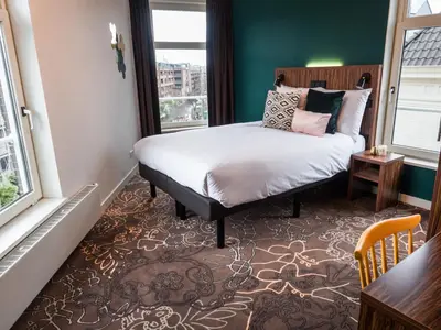 a bedroom with a bed and a large window at Linden Hotel in Amsterdam