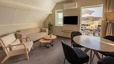 a living room with a couch and a table and chairs at Strandstudio's Camperduin in Schoorl