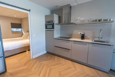 a small kitchen with a sink and a bed at Strandstudio's Camperduin in Schoorl