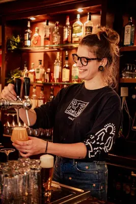 a woman standing at a bar preparing a drink at Long John's Pub & Hotel in Amersfoort