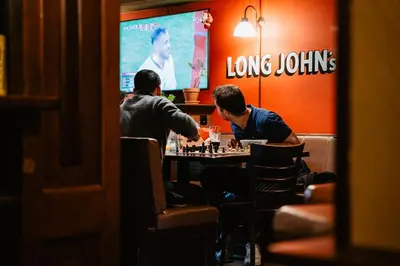 two men sitting at a table playing chess in a restaurant at Long John's Pub & Hotel in Amersfoort