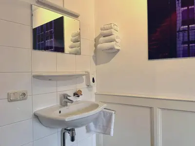 a bathroom with a sink and a mirror and towels at Long John's Pub & Hotel in Amersfoort