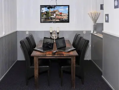 a dining room table with four chairs with laptops on it at Hotel Royal in IJmuiden