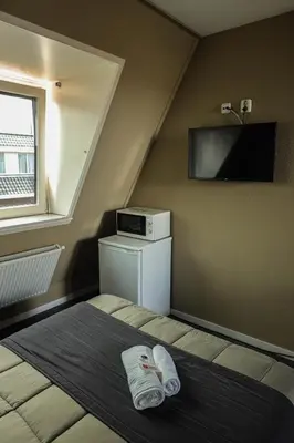 a bedroom with a bed with a tv on the wall at Hotel Royal in IJmuiden