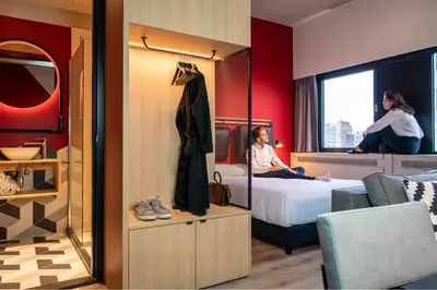 a hotel room with a bed and two people sitting on a bed at Via Amsterdam in Amsterdam