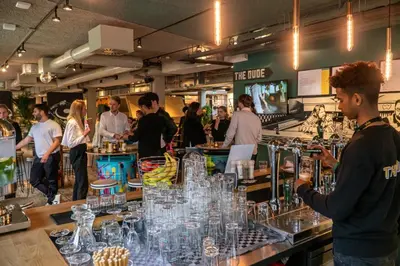 a group of people standing around a bar with glasses at Via Amsterdam in Amsterdam
