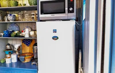a microwave on top of a refrigerator in a kitchen at Het Edamse Vissershuisje in Edam