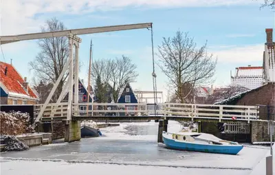 a bridge over a river with a boat in the water at Het Edamse Vissershuisje in Edam