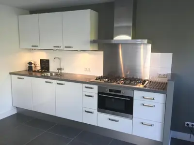 a kitchen with white cabinets and a stove top oven at Salt Life Beachhouse in Noordwijk aan Zee