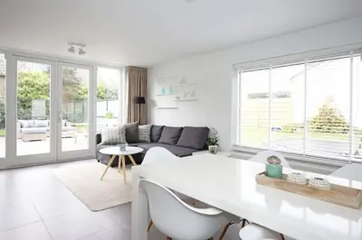 a white living room with a couch and a table at Salt Life Beachhouse in Noordwijk aan Zee