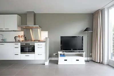 a kitchen with a tv on a white stand with a tvictericter at Salt Life Beachhouse in Noordwijk aan Zee