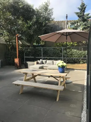 a picnic table with a couch and an umbrella at Salt Life Beachhouse in Noordwijk aan Zee