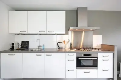 a kitchen with white cabinets and a stove top oven at Salt Life Beachhouse in Noordwijk aan Zee