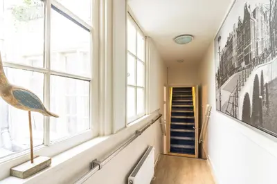a hallway with windows and a staircase with a painting at Patrick's Place in Amsterdam
