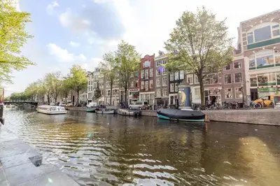 a river with boats in a city with buildings at Patrick's Place in Amsterdam