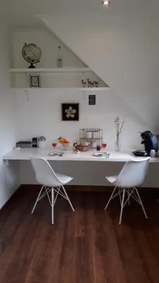 a white counter with two white chairs in a room at B & B De Gouwe Plek in Hoogwoud
