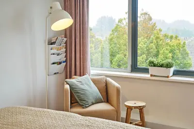a living room with a chair and a window at Amrâth Apart-Hotel Schiphol Badhoevedorp in Badhoevedorp