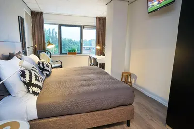 a hotel room with a bed and a window at Amrâth Apart-Hotel Schiphol Badhoevedorp in Badhoevedorp