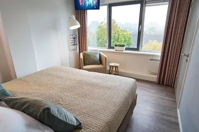 a bedroom with a bed and a chair and a window at Amrâth Apart-Hotel Schiphol Badhoevedorp in Badhoevedorp