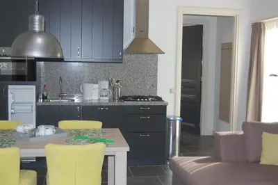 a kitchen with blue cabinets and a table with yellow chairs at De Willigen Logies in Vreeland