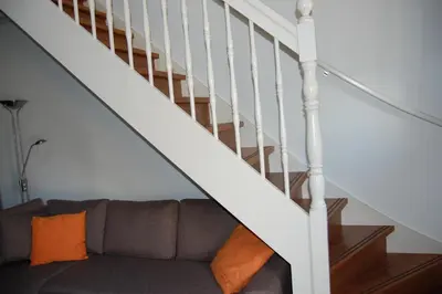 a living room with a couch under a staircase at De Willigen Logies in Vreeland